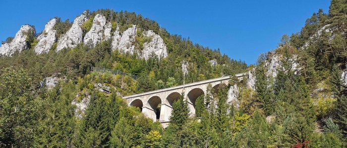 Motorradurlaub im Burgenland © Leberzipf Didi Steinbogenbrücke in bewaldeten Bergen unter blauem Himmel