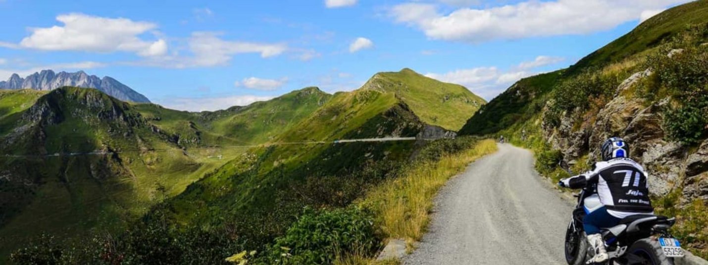 Motorrad-Emotion mit Genuss Motorradfahrer auf Bergstraße mit grünen Bergen und blauem Himmel
