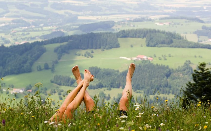 Goldener Herbst auf der Mühl4tler Alm Zwei Personen liegen im Blumenfeld mit erhobenen Beinen vor Landschaft