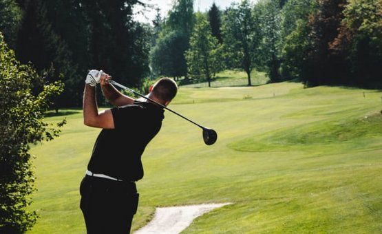 Golfwoche Mann schlägt Golfball auf einem sonnigen Golfplatz