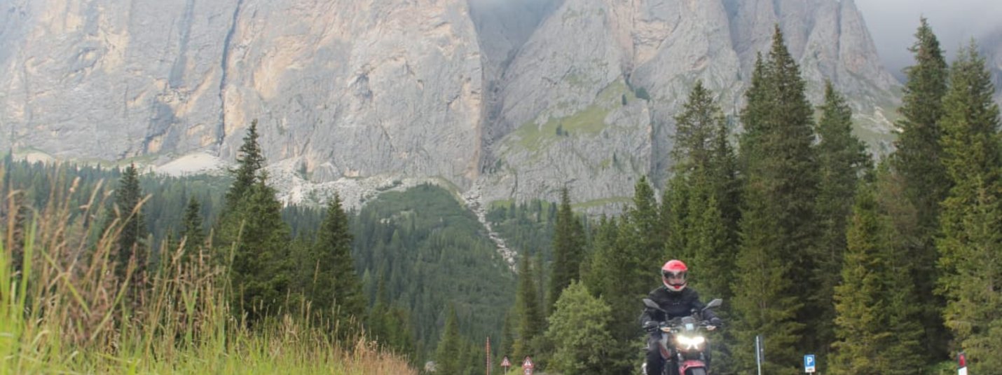3 Tage Südtirol Motorrad Urlaub Motorradfahrer auf Landstraße vor nebligen Bergen und Nadelwald