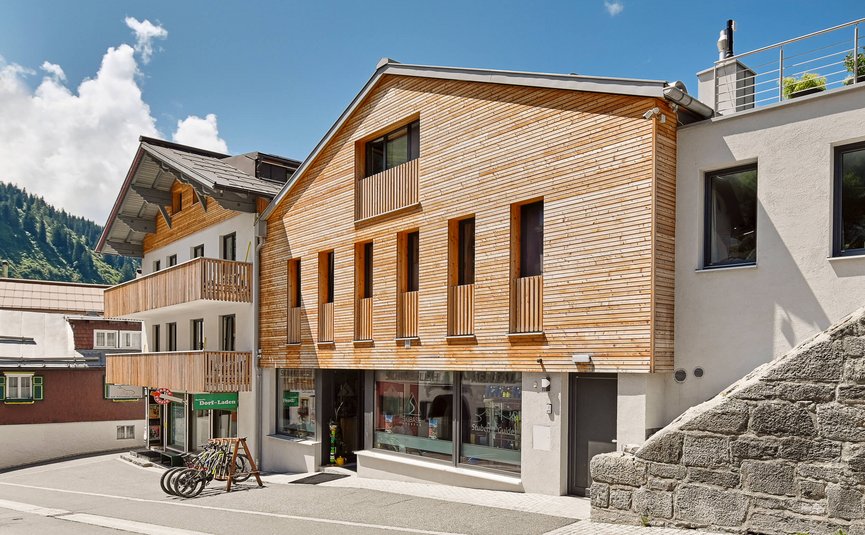 Straße mit modernen Häusern aus Holz und Stein unter blauem Himmel