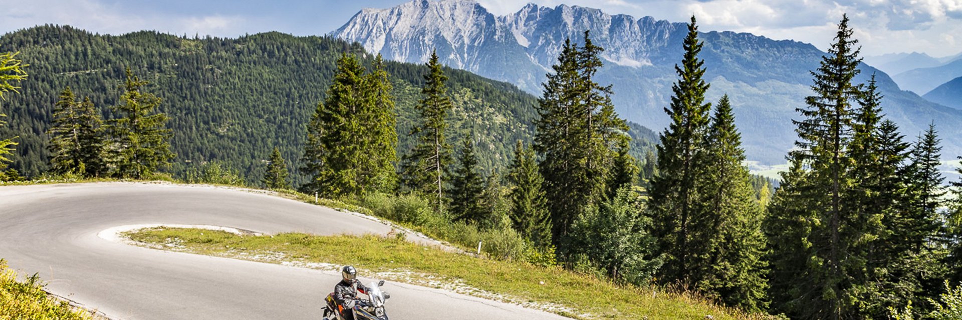 Obersteiermark – Ausseerland – Salzkammergut © Alexander Seger Motorradfahrer auf kurviger Bergstraße mit Tannen und Bergen im Hintergrund