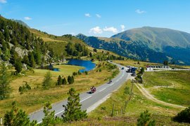 Motorradurlaub im Mölltal – Großglockner – Nockalm © Land Kärnten - Großglockner Hochalpenstraßen AG Gebirgsstraße mit Motorradfahrern, See und bewaldeten Bergen im Sommer