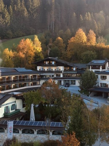 Berghotel mit Solarpaneelen umgeben von Herbstwald und Nebel