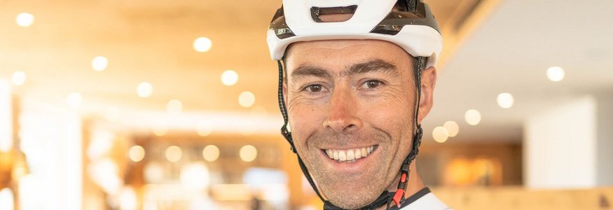 So geht Gravelbike-Urlaub im Hotel Cristallo
 © Andrea Acler Lächelnder Radfahrer mit Helm in Sport- und Wellnesshotelumgebung