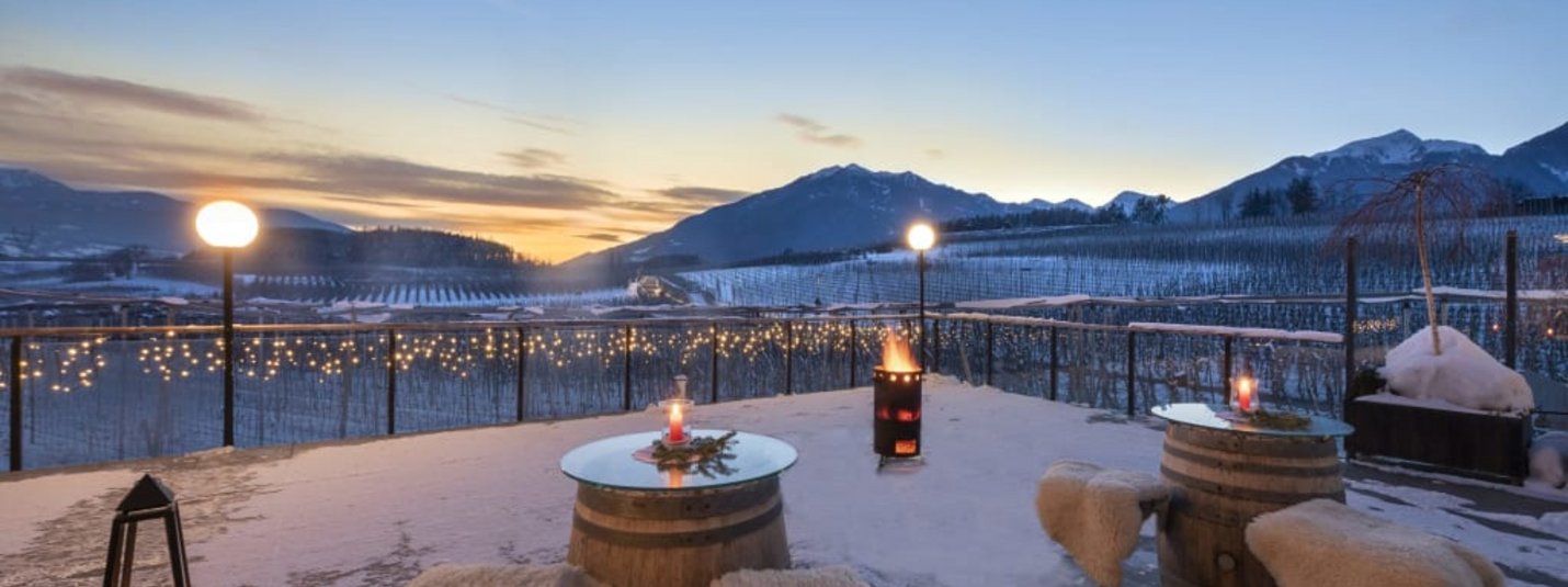 Weihnachtszauber im Jonathan 5 Nächte Winterterrasse mit Fässern als Tische und Schafsfell-Stühlen bei Sonnenuntergang