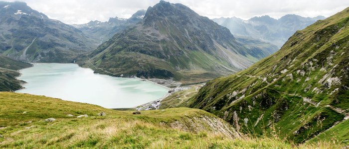 Paznaun – Silvretta © Montafon Tourismus GmbH - Andreas Haller Bergsee und grüne Alpenhänge bei bewölktem Himmel