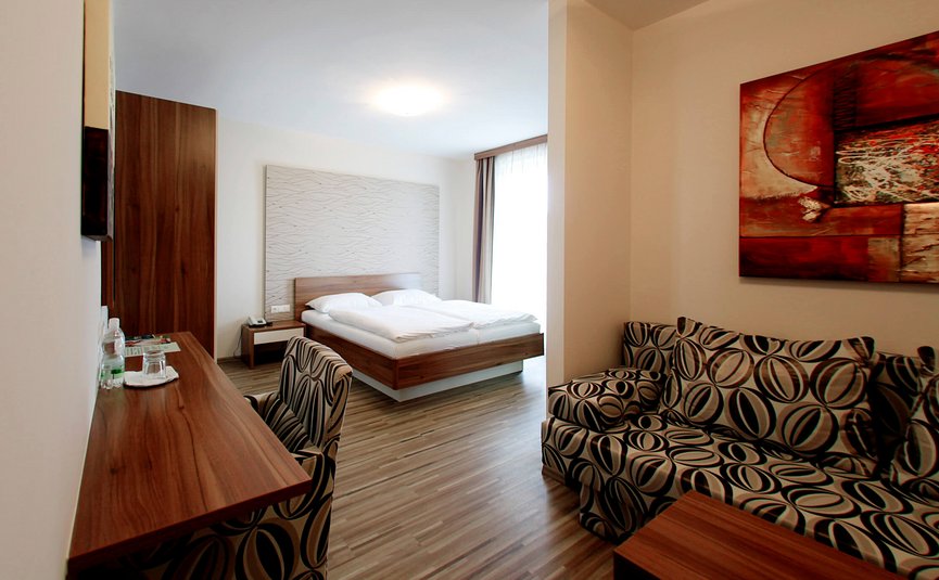 Modern eingerichtetes Hotelzimmer mit Doppelbett und Sitzbereich