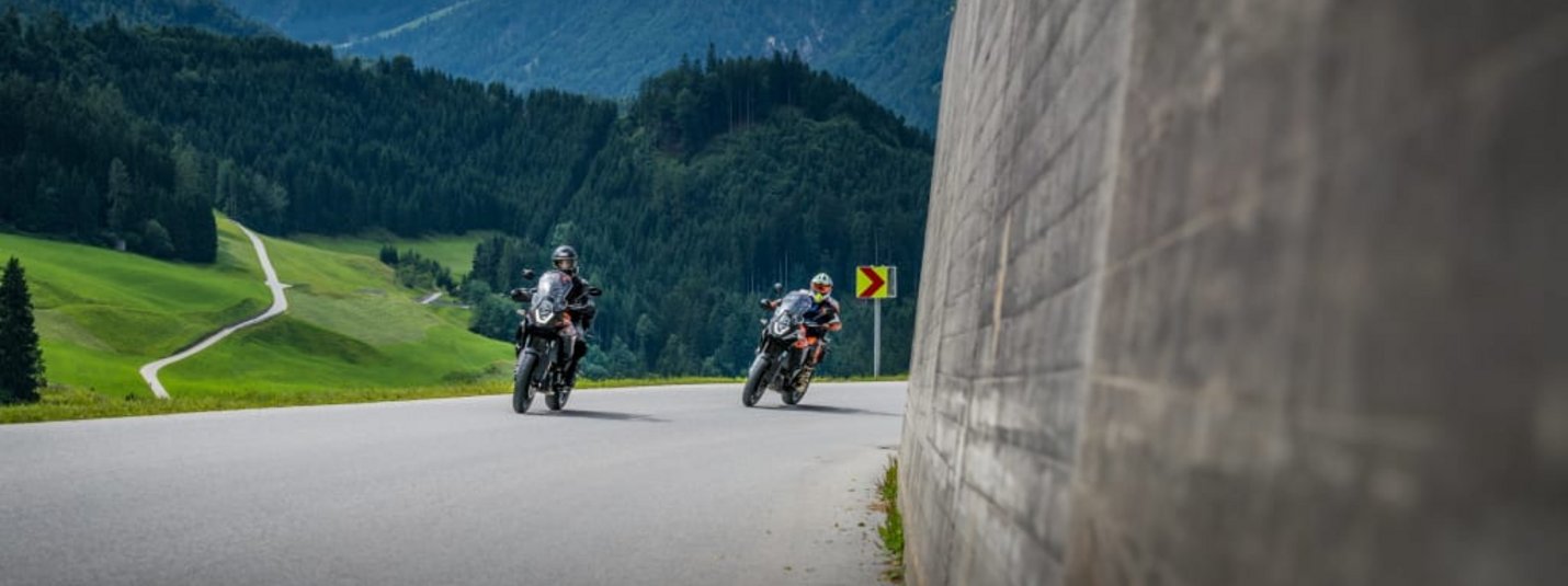 6 Tage Motorradfahren im Zillertal Zwei Motorradfahrer auf Bergstraße mit Wald und Bergen im Hintergrund