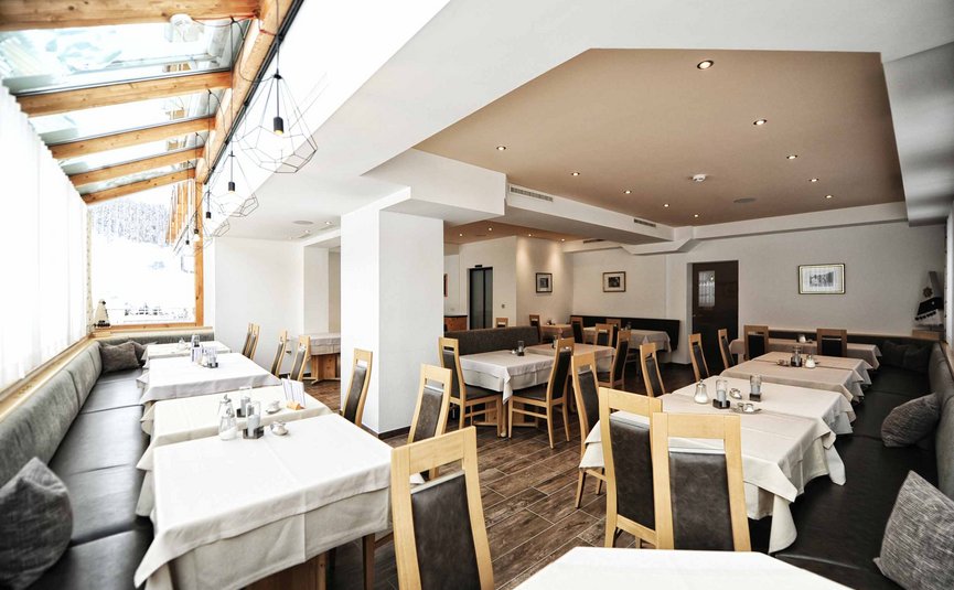 Leerer moderner Speisesaal mit Holzmöbeln und weißen Tischdecken.
