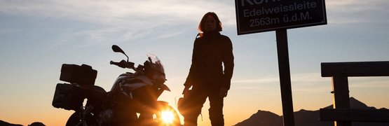 Auf die Berge - fertig - los ! ab € 398,- pro Person Person neben Motorrad an einem Bergpass bei Sonnenuntergang