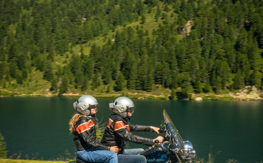 Hotel & Südtiroler Gasthaus Der Gassenwirt *** © Moppetfoto.de Zwei Personen fahren auf einem Motorrad neben einem See in den Bergen