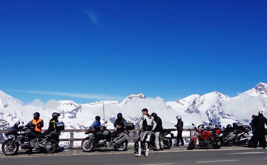 Kurvenkönig Special ab € 208,- pro Person Motorradfahrer mit Bikes an Aussichtspunkt in verschneiter Berglandschaft