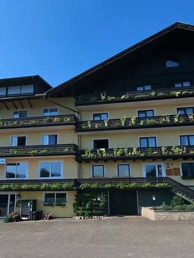 Motorradurlaub © Gast-Hof-Laden Schneeweiss Großes uriges Chalet mit Balkonpflanzen bei klarem Himmel