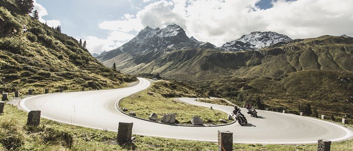 Montafon – Silvretta © Christoph Schöch Motorradfahrer auf kurviger Bergstraße mit schneebedeckten Gipfeln