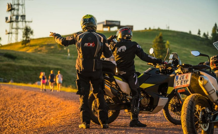 4 Touren Bike Woche Zwei Motorradfahrer in Schutzkleidung beraten sich auf einem Landweg bei Sonnenuntergang