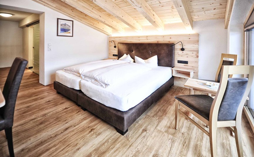 Modernes Schlafzimmer mit Holzbalkendecke und Bett mit braunem Kopfteil