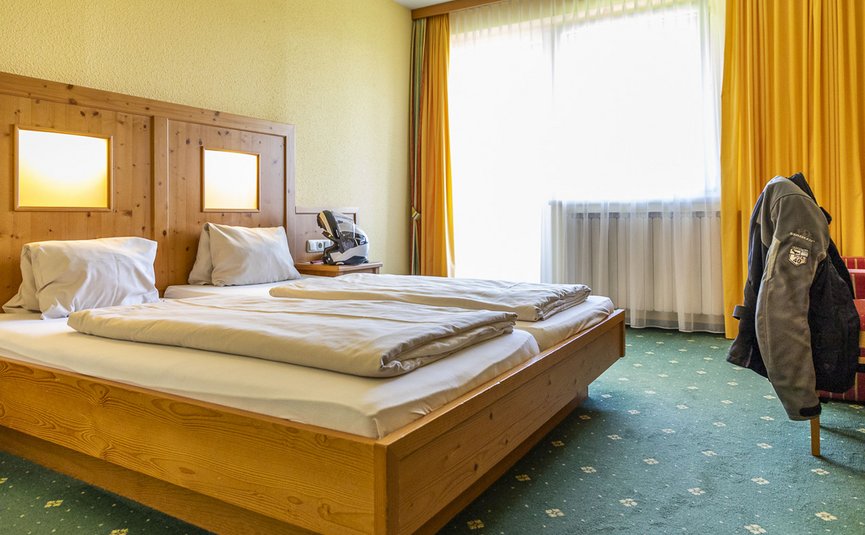 Helles Hotelzimmer mit zwei Einzelbetten und gelben Vorhängen