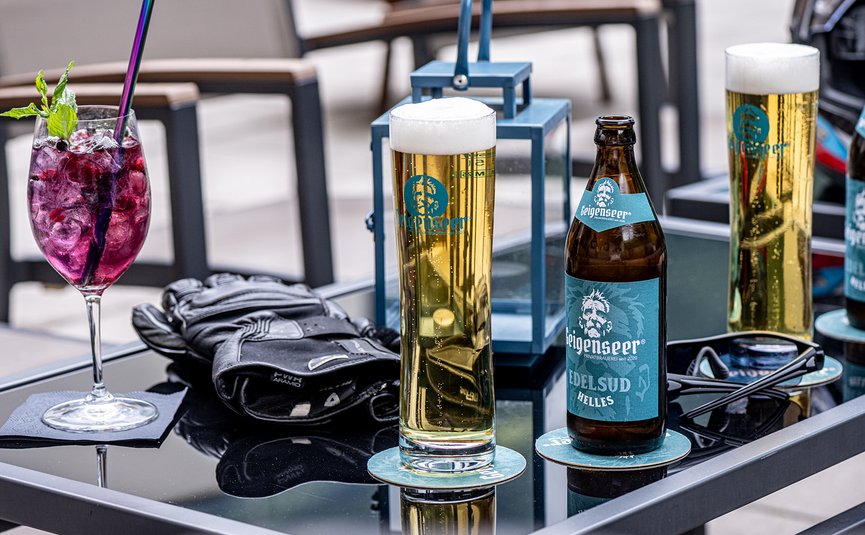 DAS UNTERRAIN lifestyle hotel **** © Armin Kleinlercher Gläser Bier und Cocktail auf einem Tisch mit Handschuhen und Brille