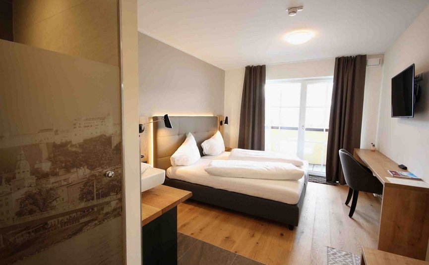 Modernes Hotelzimmer mit Doppelbett und Schreibtisch am Fenster