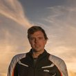 Mann steht neben KTM-Motorrad bei Sonnenuntergang in den Bergen