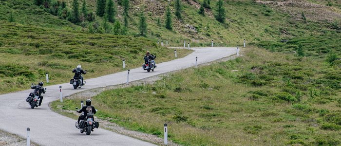 DAS UNTERRAIN lifestyle hotel **** © Armin Kleinlercher Vier Motorradfahrer fahren eine kurvige Straße in einer grünen Berglandschaft