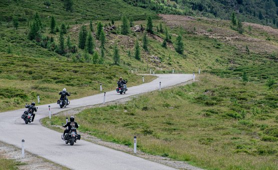 Motorradurlaub in Osttirol – Großglockner – Lienzer Dolomiten © Armin Kleinlercher Vier Motorradfahrer fahren eine kurvige Straße in einer grünen Berglandschaft
