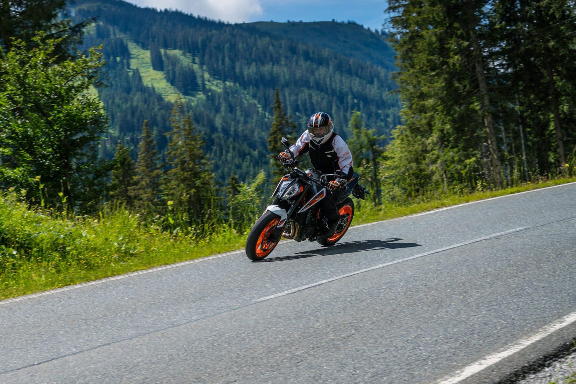 Motorradurlaub © Moppetfoto.de Motorradfahrer auf kurviger Bergstraße mit Bäumen und Bergen im Hintergrund