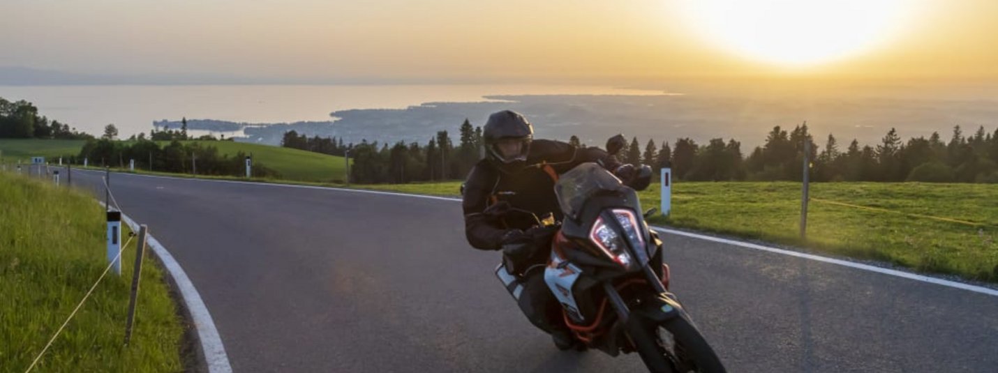Motorradfahrer fährt auf Landstraße bei Sonnenuntergang