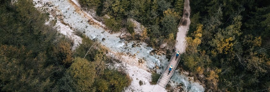 Gravel-Wochenende in San Vigilio © Jens Scheibe Luftaufnahme von Wanderern auf einer Brücke über einen Fluss im Wald