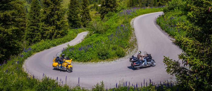 Arlberg – Dreiländereck © Moppetfoto.de Zwei Motorräder auf einer kurvigen Bergstraße in grüner Alpenlandschaft