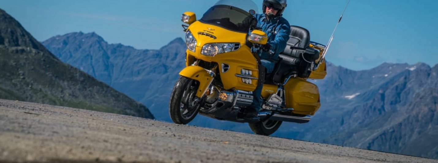Volltreffer für Biker Mann fährt Motorradtour auf gelbem Motorrad in den Bergen