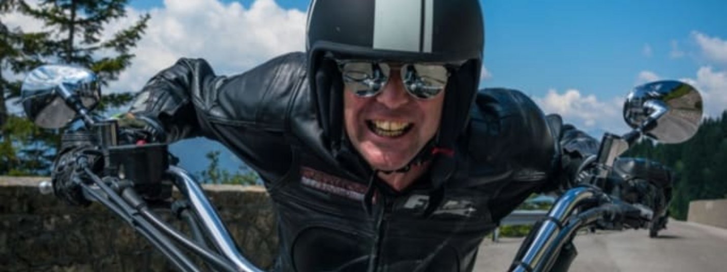 Stornofrei Mann auf Motorrad mit Helm und Lederjacke vor blauem Himmel mit Schrift Bikerweeks