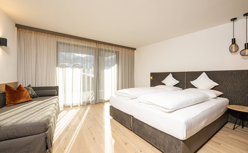 MOAR'S Hotel ***S © Harald Wisthaler Hell eingerichtetes Schlafzimmer mit Doppelbett und Sofa bei Tageslicht