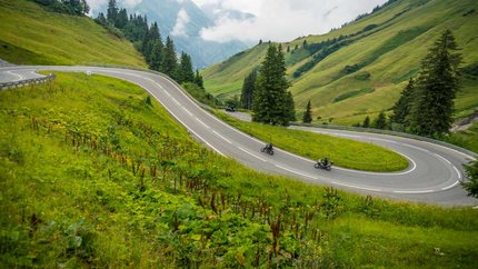 Lechtal – Hahntennjoch © Moppetfoto.de Kurvige Bergstraße mit zwei Motorradfahrern und grünen Hügeln