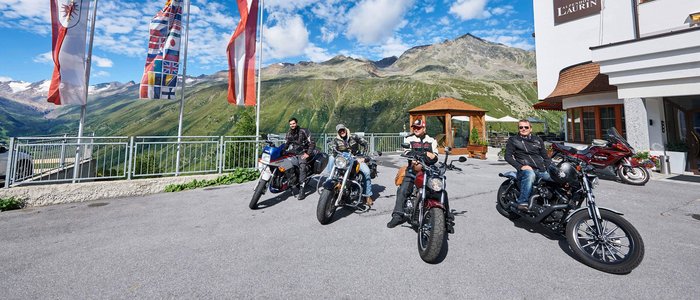 Alpenhotel Laurin ***S © studio22.at - Marcel Hagen Vier Motorradfahrer vor Alpenhotel Laurin mit Bergen und Fahnen im Hintergrund