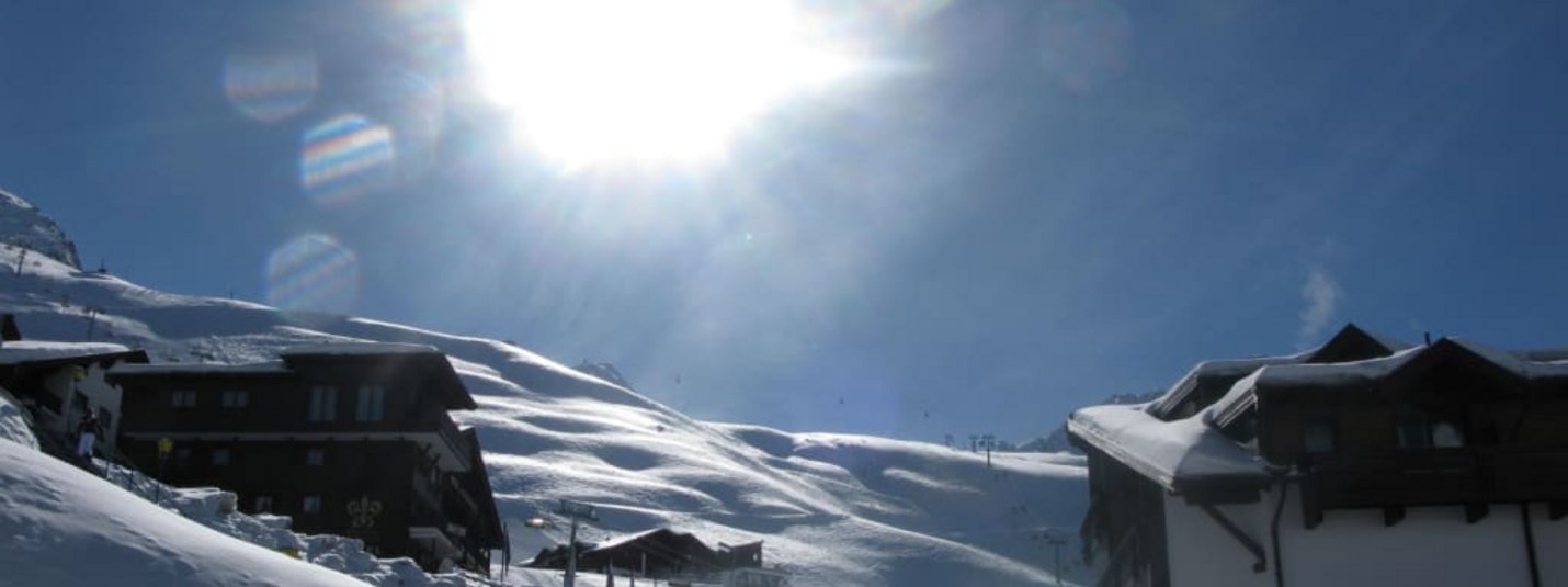 Sonnenschilauf-Pauschale Sonniger Wintertag mit verschneiten Häusern und Bergen