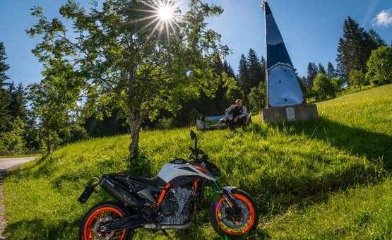 Motorradurlaub in der Region Hochkönig © Moppetfoto.de Motorrad auf grüner Wiese mit Baum und Person im Hintergrund bei Sonnenschein