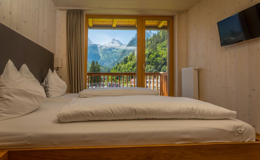 Gemütliches Zimmer mit Doppelbett und Bergblick vom Balkon