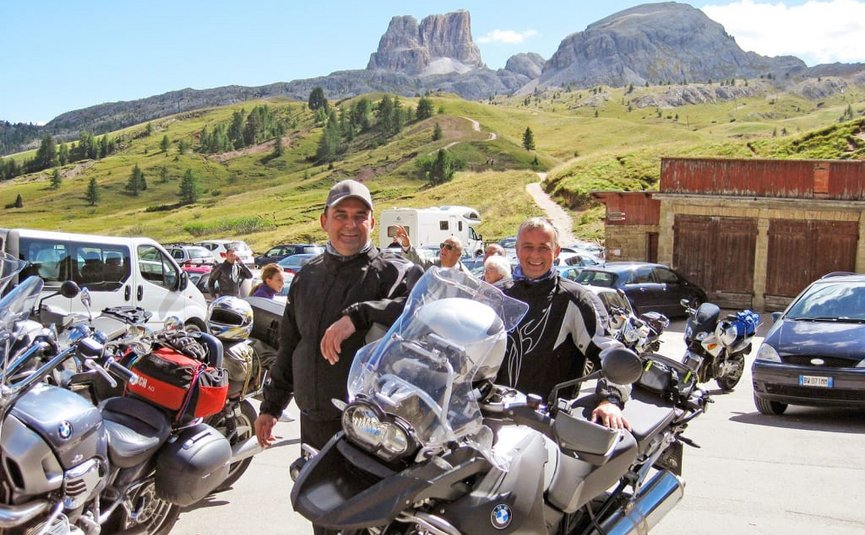 Kurvenkönig Special ab € 208,- pro Person Zwei Motorradfahrer vor Berglandschaft und Motorrädern bei sonnigem Wetter