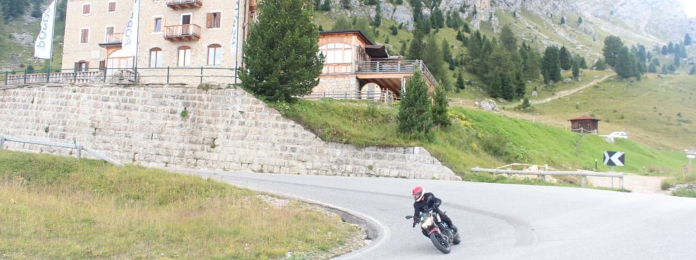 5 Tage Südtirol Motorrad Urlaub Motorradfahrer auf kurviger Straße vor Hotel Pordoi in den Bergen