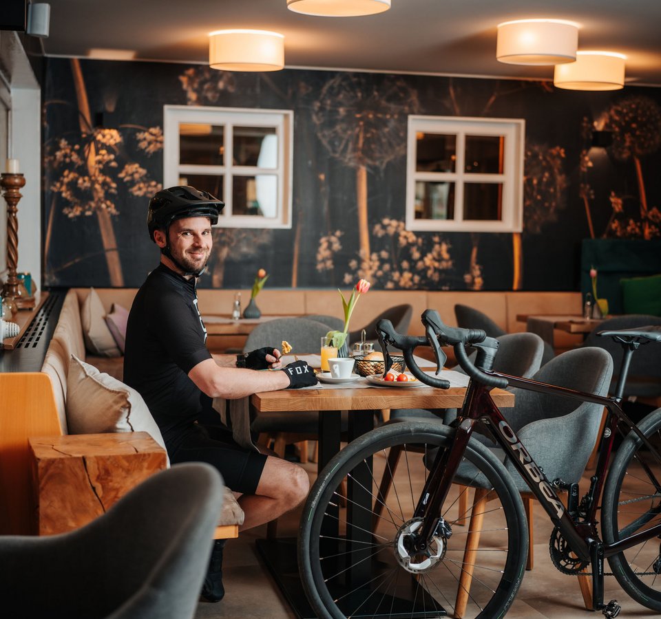 Gravelabenteuer zwischen See & Nockbergen © Martin Hoffmann Mann mit Fahrradhelm sitzt in Café und isst