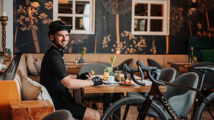 Gravelabenteuer zwischen See & Nockbergen © Martin Hoffmann Mann mit Fahrradhelm sitzt in Café und isst