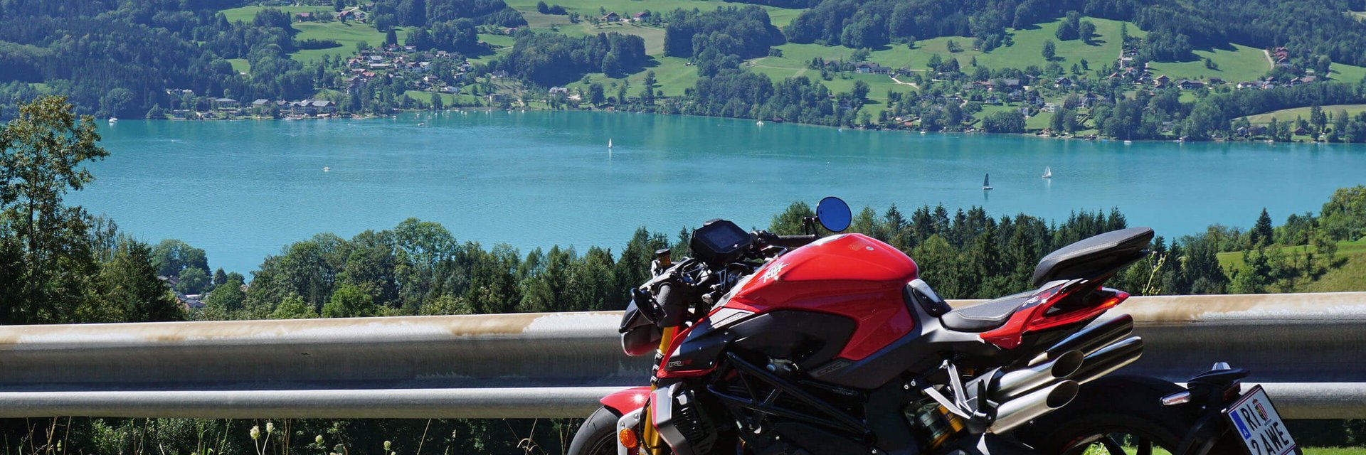 Gast-Hof-Laden Schneeweiss *** © Armin Hoyer Rotes Motorrad auf Bergstraße mit See und Hügeln im Hintergrund