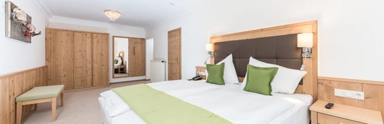 Golfwoche Hell eingerichtetes Hotelzimmer mit Doppelbett und grüner Bettwäsche