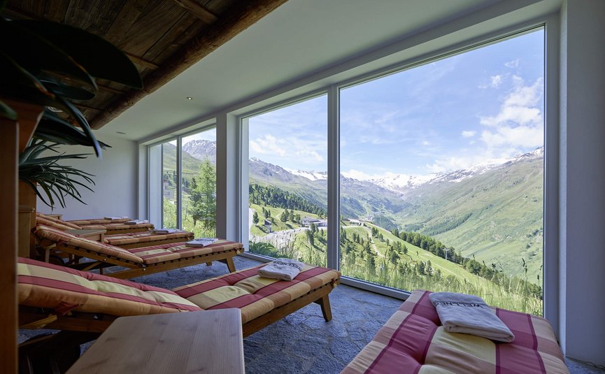Alpenhotel Laurin ***S © studio22.at - Marcel Hagen Ruheliegen vor großen Fenstern mit Blick auf grüne Berge und schneebedeckte Gipfel