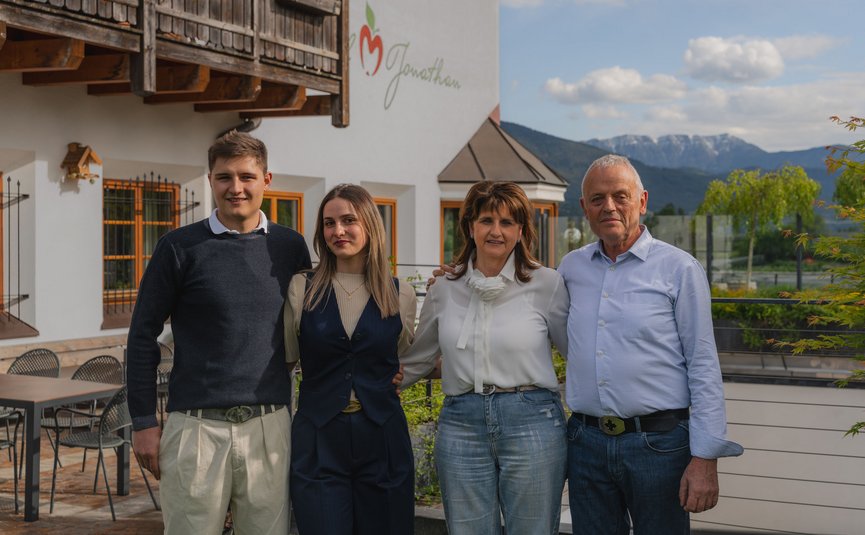 Familienfoto vor einem Haus mit Bergen im Hintergrund