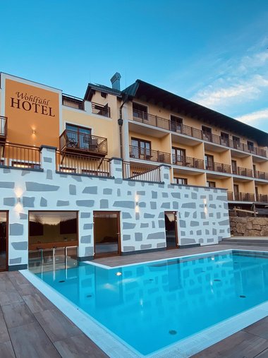 Motorradurlaub © Wohlfühlhotel Rockenschaub Hotelgebäude mit Außenpool bei klarem Himmel