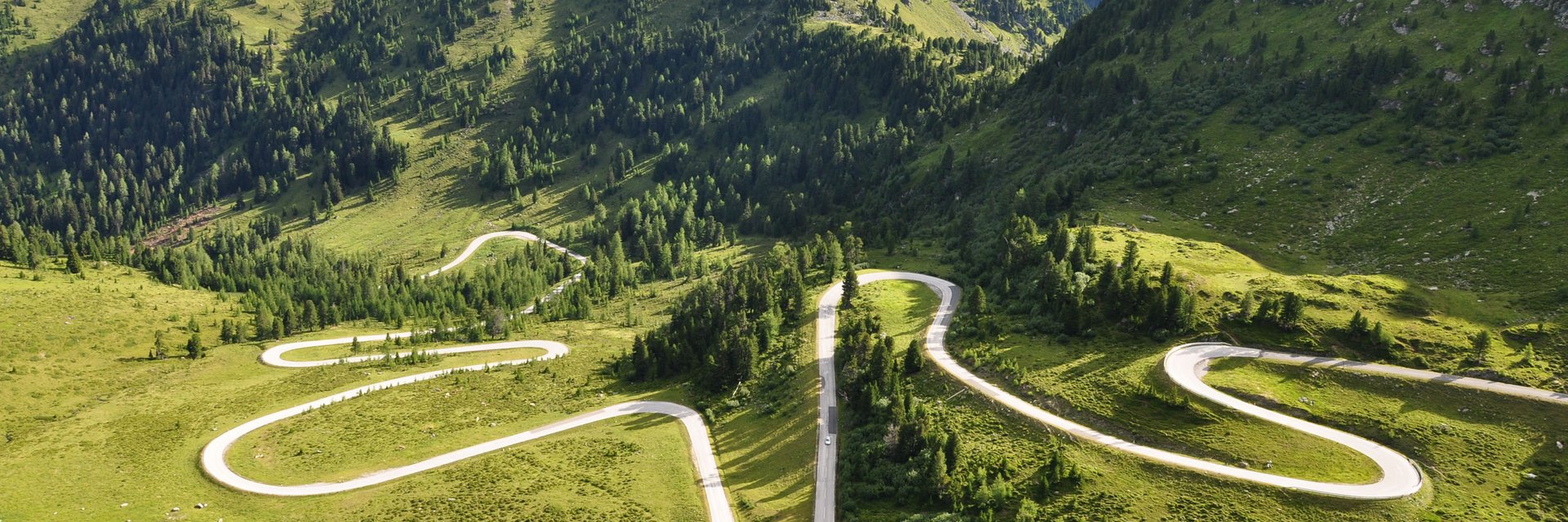 Erlebnishotel Kärnten-Mölltal ***S © Land Kärnten - Großglockner Hochalpenstraßen AG Serpentinenstraße in grünen, bewaldeten Bergen bei Tageslicht